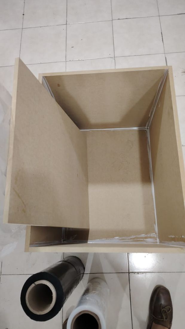 Caja de MDF abierta con rollos de film de embalaje al lado