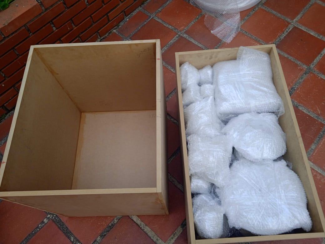Caja de MDF vacía junto a otra llena de piezas envueltas